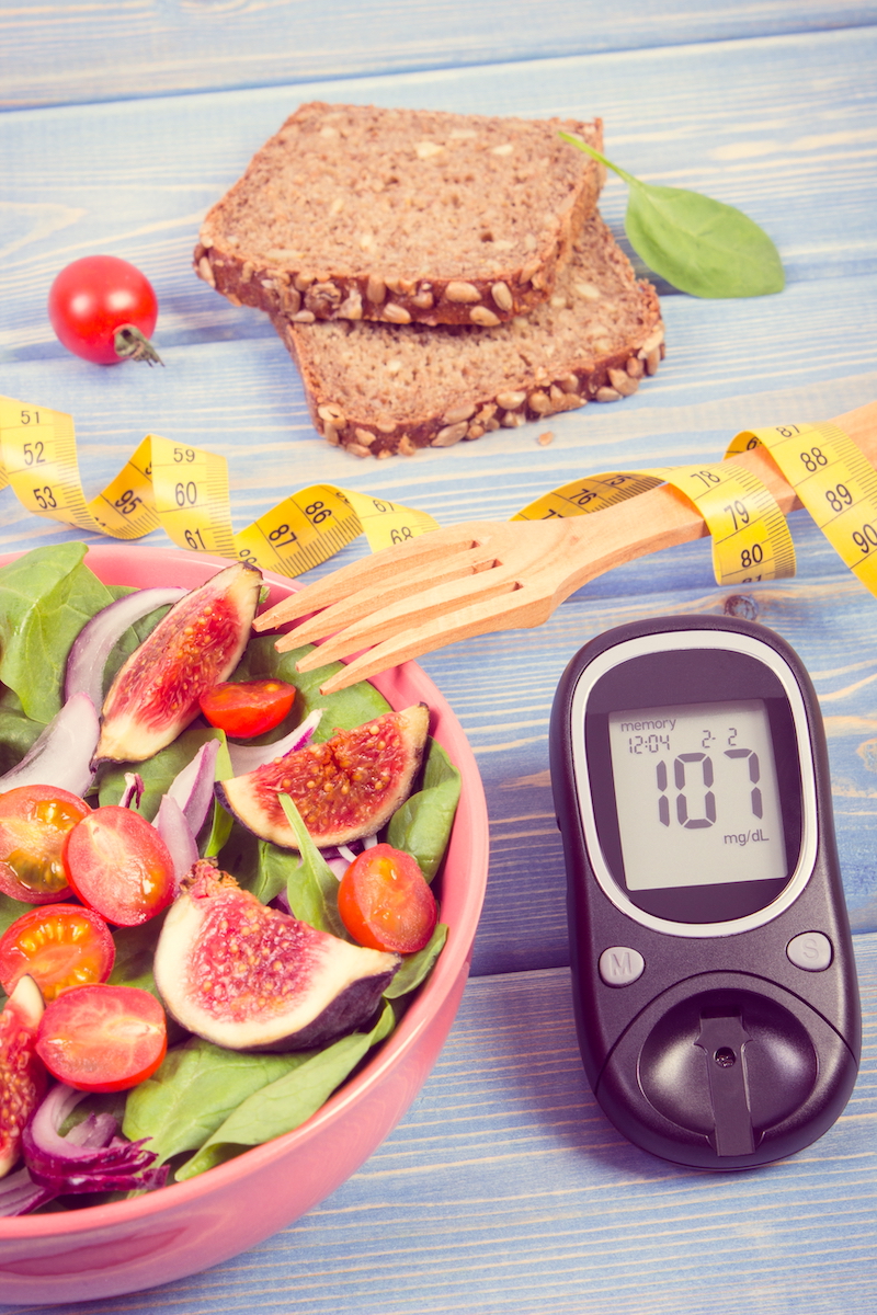 Fruit and vegetable salad, glucose meter with result of measurement sugar level and tape measure, concept of diabetes, diet, slimming, healthy lifestyles and nutrition